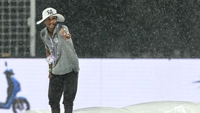 A groundsman gestures as he covers the pitch after rain stopped play during the IPL 2026 match between KKR and PBKS. (AFP)