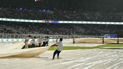 Groundsmen cover the field as rain halts play during the 2026 Indian Premier League (IPL) T20 match between Kolkata Knight Riders and Mumbai Indians at the Eden Gardens in Kolkata on May 20 (AFP)