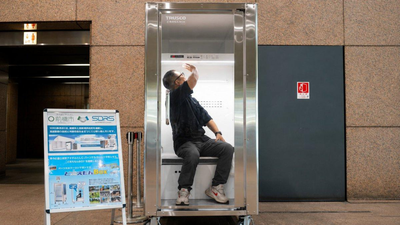 A person demonstrates Japan's TRUSCO Do Reimon Box, a walk-in cooling booth. Japan built a 'human refrigerator' that cools your body in just 5 minutes, and it could transform how workers beat extreme heat