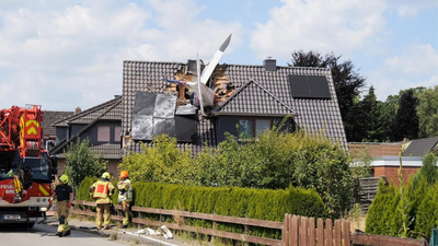 Emergency services at the scene after a small plane crashed lodged in the roof of a house, in Ganderkesee Two killed after small plane crashes into house in Germany