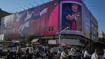 Motorcyclists ride past a billboard depicting US President Donald Trump inside a catering container in downtown Tehran, Iran Iran war at 6 months: Who gained, who lost the most economically