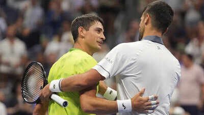 Novak Djokovic, right, embraces Mariano Navone after Navone won their match. (AP Photo) US Open: Mariano Navone wins battle as Novak Djokovic’s body says no