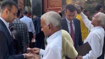 A viral video from outside the UPPSC headquarters in Prayagraj shows a father fixing his son’s coat, combing his hair and feeding him sweets before his interview. The son then seeks his father’s blessings, touching his feet before entering the interview venue. (Screengrab from social media video) Before son’s big UPPSC interview, father fixes his coat, combs his hair and feeds him sweets; viral video melts hearts