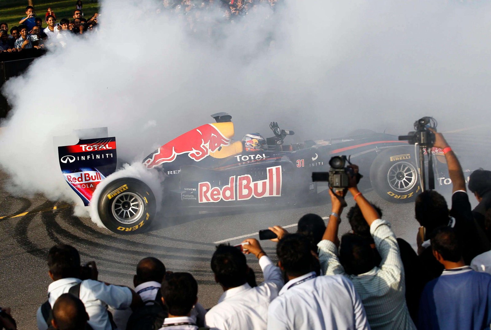 Red Bull Formula One reserve driver Daniel Ricciardo drives near the India Gate during his team's road show in New Delhi