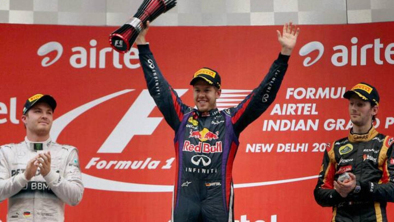 Sebastian Vettel celebrates with the winner's trophy as runner-ups Rosberg (L) and Grosjean of Lotus