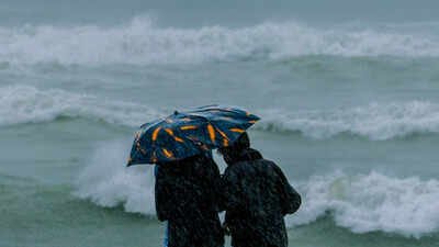 File photo: Two people holding an umbrella brave strong winds and rain as high tide waves hit the coast ahead of the impending landfall of cyclonic storm 'Arnab', in Visakhapatnam, Andhra Pradesh. Aviation ministry suspends operations at three Andhra airports as Cyclone Arnab intensifies